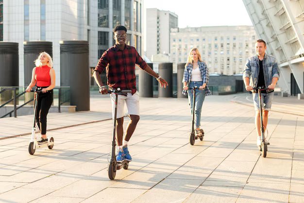 Quatre jeunes adultes à trottinette électrique sur une esplanade pavée en ville – réglementation de la trottinette en France
