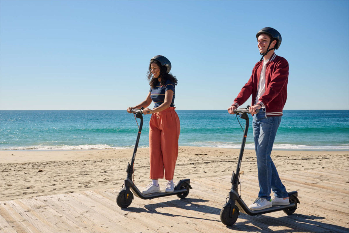 Deux personnes casquées sur leur trottinette électrique, sur une promenade au bord de la mer – et pour aller au travail ?