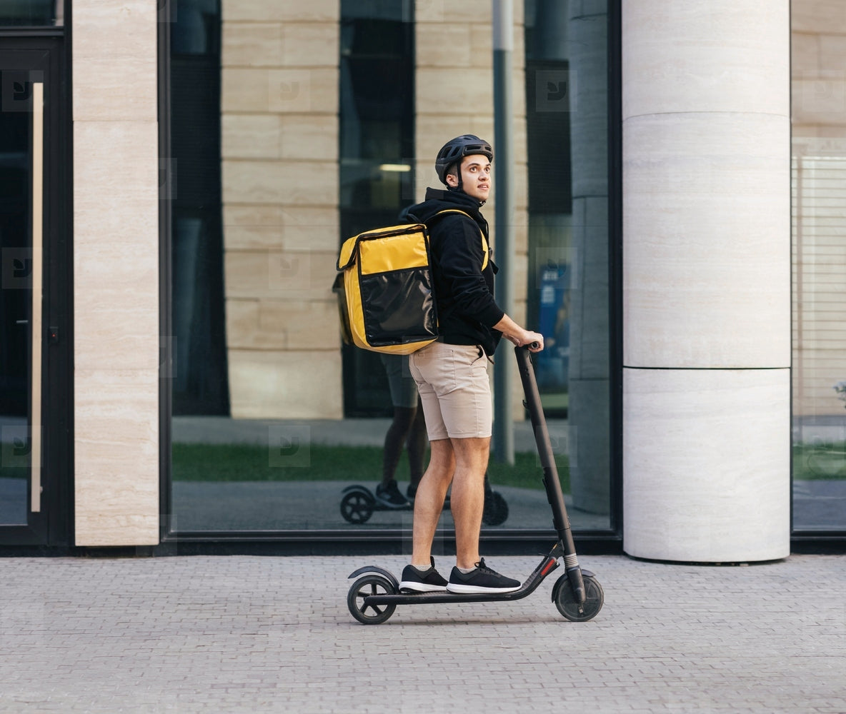 Coursier en trottinette électrique livrant en ville