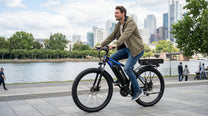 Homme roulant sur le vélo électrique Duotts C29-K sur une allée au bord d'un lac