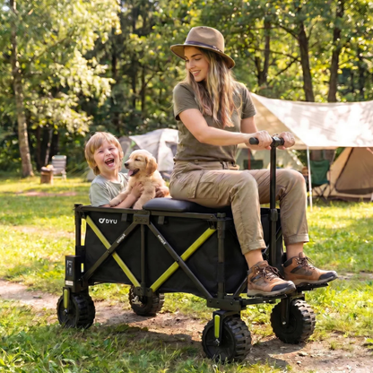DYU CampX sur l’herbe près d’une tente, une femme assise sur le chariot et un enfant avec un chiot dedans