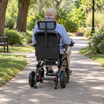 Homme âgé assis dans le fauteuil roulant électrique EASWE B10 de dos sur une allée