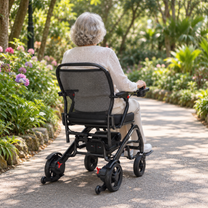 Femme âgée assise dans le fauteuil roulant électrique EASWE C20 de dos dans un jardin