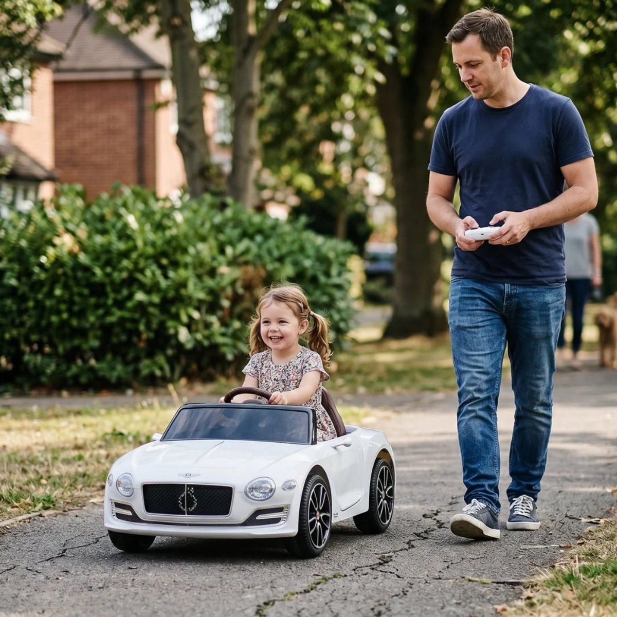Enfant au volant de la voiture électrique pour enfants Bentley EXP 12 avec un adulte à côté