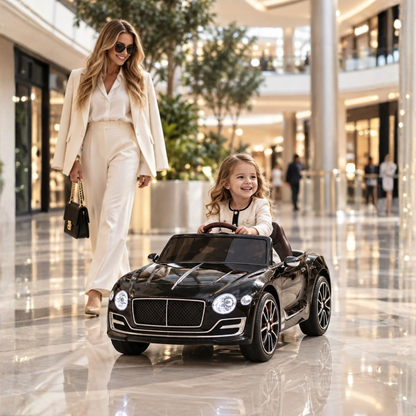 Enfant au volant de la voiture électrique pour enfants Bentley EXP 12 avec un adulte à côté