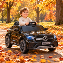 Enfant au volant de la voiture électrique pour enfants Mercedes GLC Coupé coloris noir dans un parc