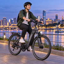 Homme à vélo sur un OneSport OT05 Max gris au bord d'un fleuve au crépuscule avec la silhouette de la ville en arrière-plan