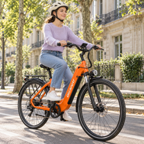 Femme casquée à vélo sur un OneSport OT05 Max orange dans une rue avec des arbres et des façades