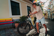 OneSport WT05 vu de profil, un homme tient le guidon tandis qu'une femme se tient derrière avec un vélo dans une rue avec des parapluies