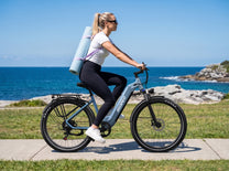 OneSport WT05 vu de profil, une femme avec un tapis de yoga sur le dos roule le long de la mer
