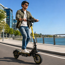 Homme avec casque roulant en trottinette électrique Wheely - H7 le long d'un quai au bord de l'eau