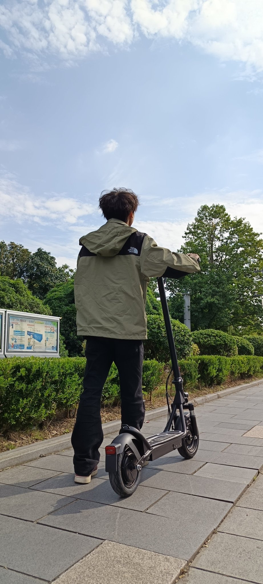 Homme roulant sur la trottinette électrique DriveTron DT01 sur une allée