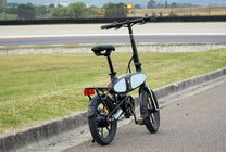 Vélo électrique pliant DYU C2, vue de trois-quarts arrière sur un chemin piéton