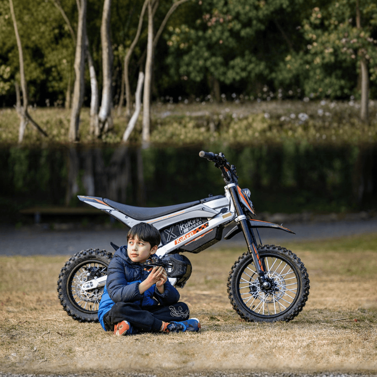 Personne assise à côté de la moto-cross électrique KuKirin X1 avec un enfant
