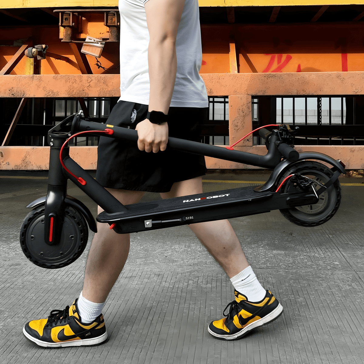 Personne portant la trottinette électrique Nanrobot H1 pliée