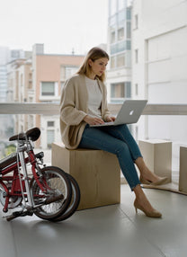 Personne assise à côté du vélo électrique pliant OneSport OT02 en ville