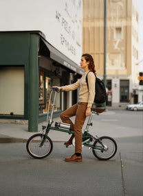 Femme debout avec le vélo électrique pliant OneSport OT02 en cours de pliage dans une rue