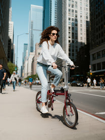 Femme roulant sur le vélo électrique pliant OneSport OT02 en ville