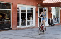 Femme roulant sur le vélo électrique pliant OneSport OT02 dans une rue