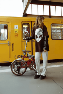 Femme debout avec le vélo électrique pliant OneSport OT02 Pro coloris rouge dans une rue