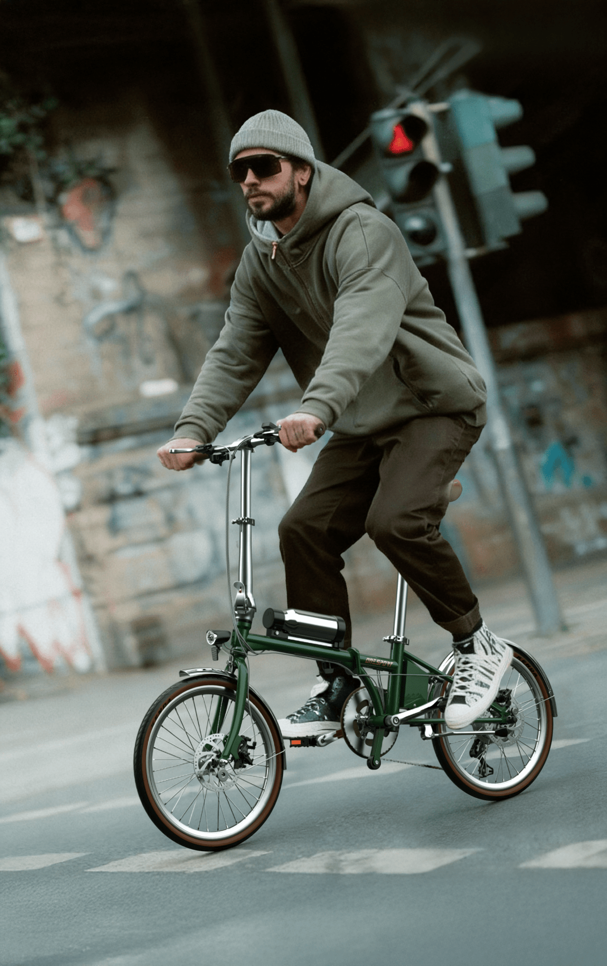 Homme roulant sur le vélo électrique pliant OneSport OT02 Pro coloris vert dans une rue