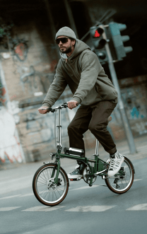 Homme roulant sur le vélo électrique pliant OneSport OT02 Pro coloris vert dans une rue