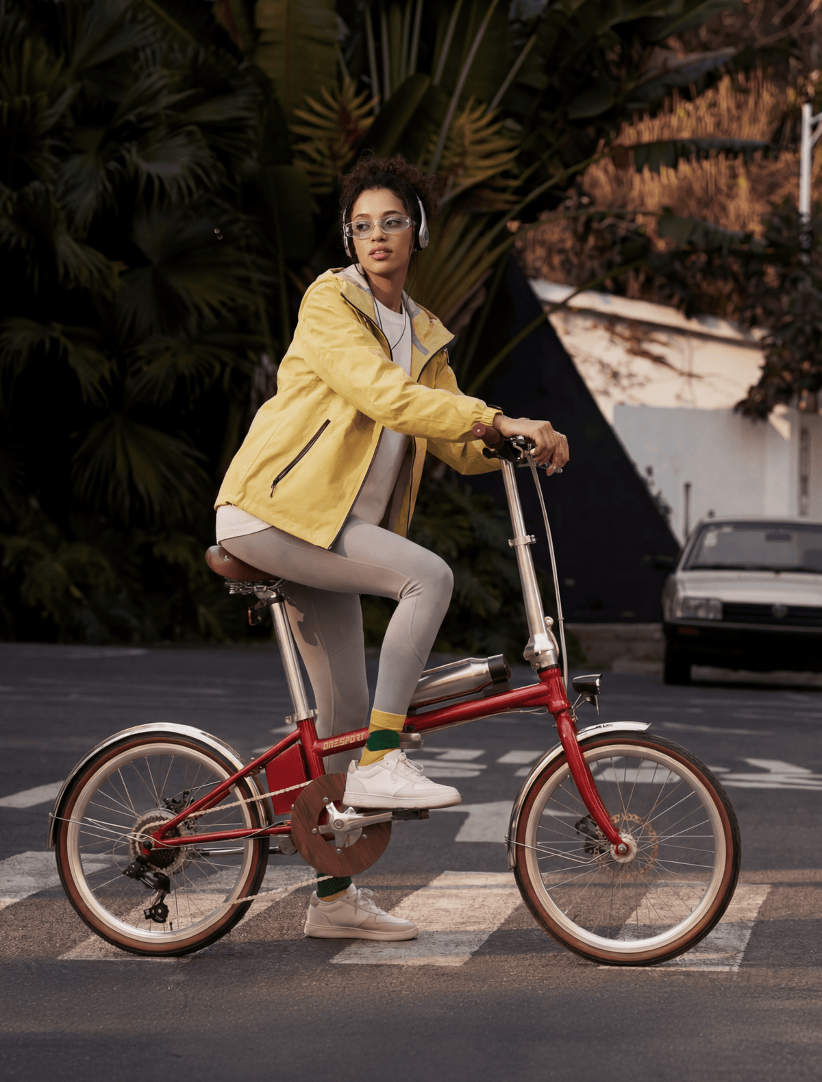 Femme roulant sur le vélo électrique pliant OneSport OT02 Pro coloris rouge dans une rue