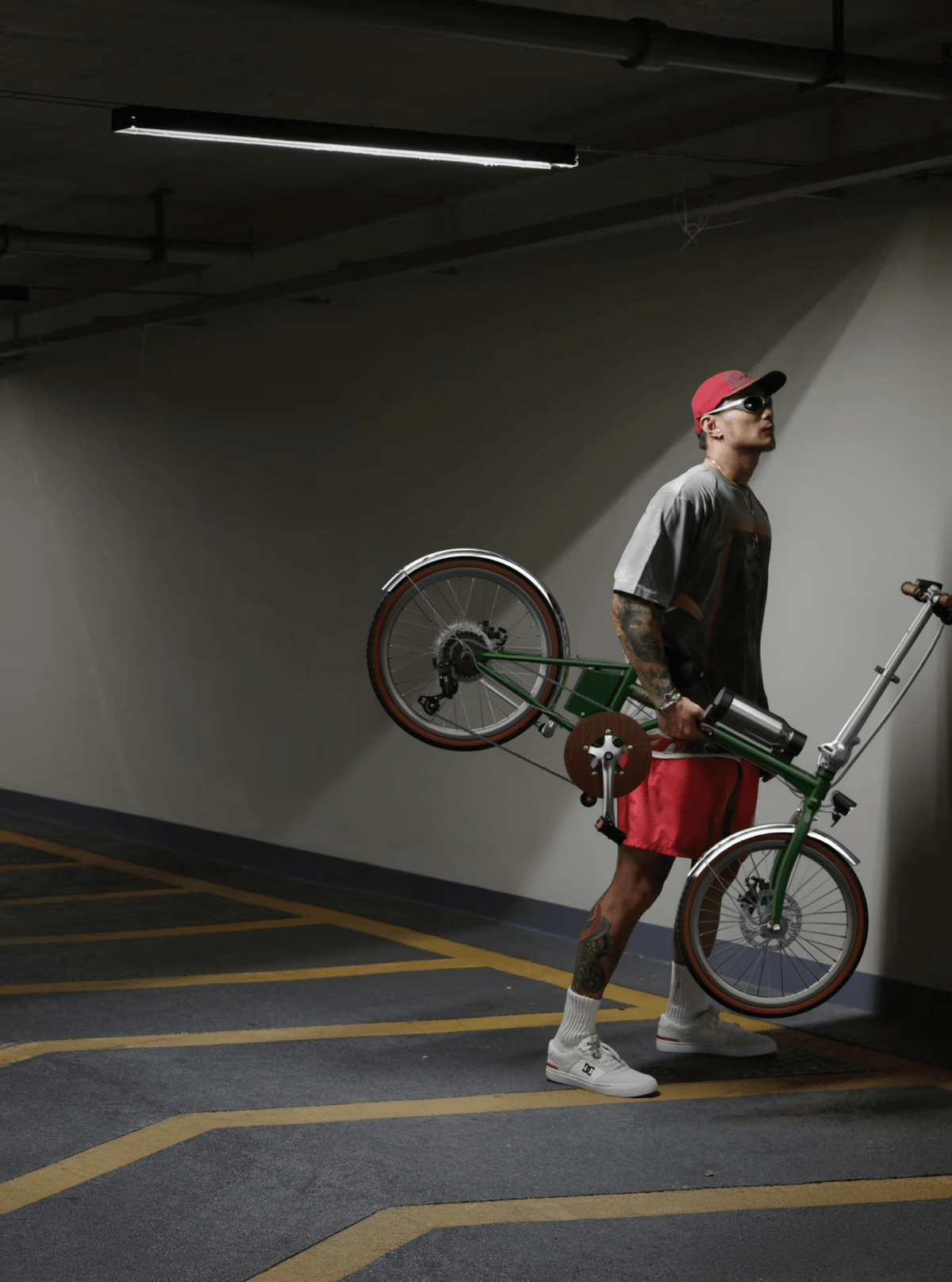 Personne debout avec le vélo électrique pliant OneSport OT02 Pro coloris vert en intérieur