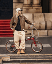 Homme debout avec le vélo électrique pliant OneSport OT02 Pro coloris rouge dans une rue