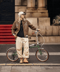 Homme debout avec le vélo électrique pliant OneSport OT02 Pro coloris vert dans une rue