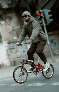 Homme roulant sur le vélo électrique pliant OneSport OT02 Pro coloris rouge dans une rue