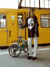 Femme debout avec le vélo électrique pliant OneSport OT02 Pro coloris vert dans une rue