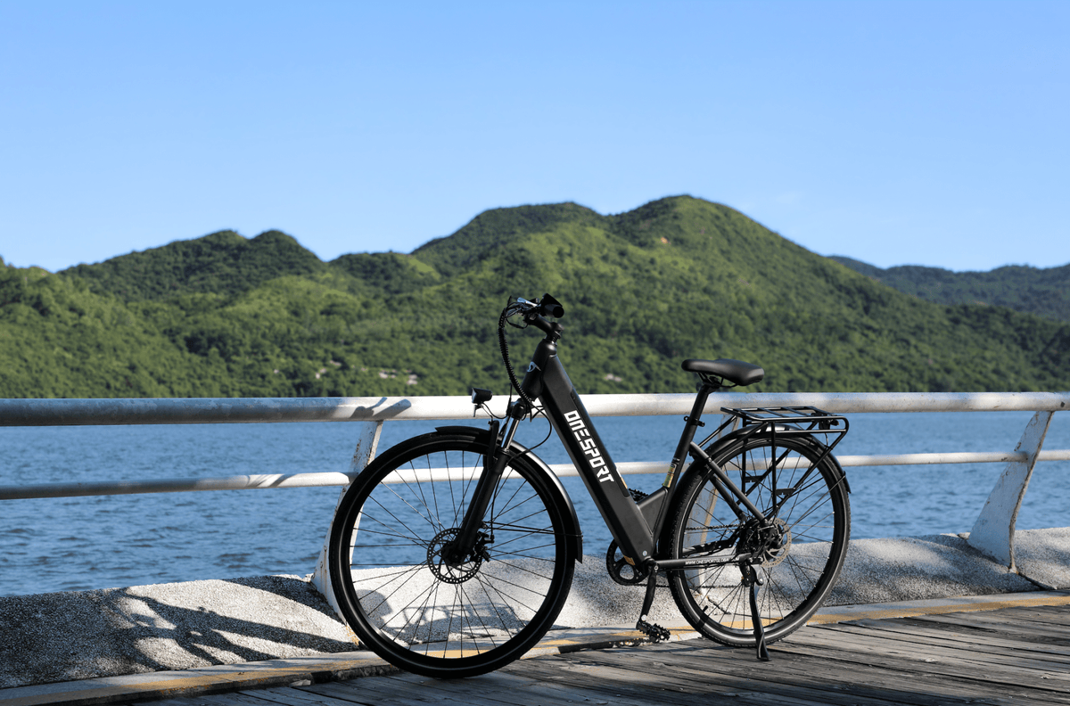 Vélo électrique OneSport OT12 vu de trois-quarts avant coloris noir au bord de la mer