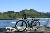 Vélo électrique OneSport OT12 vu de trois-quarts avant coloris noir au bord de la mer