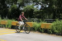Personne roulant sur le vélo électrique OneSport OT12 coloris noir dans un parc