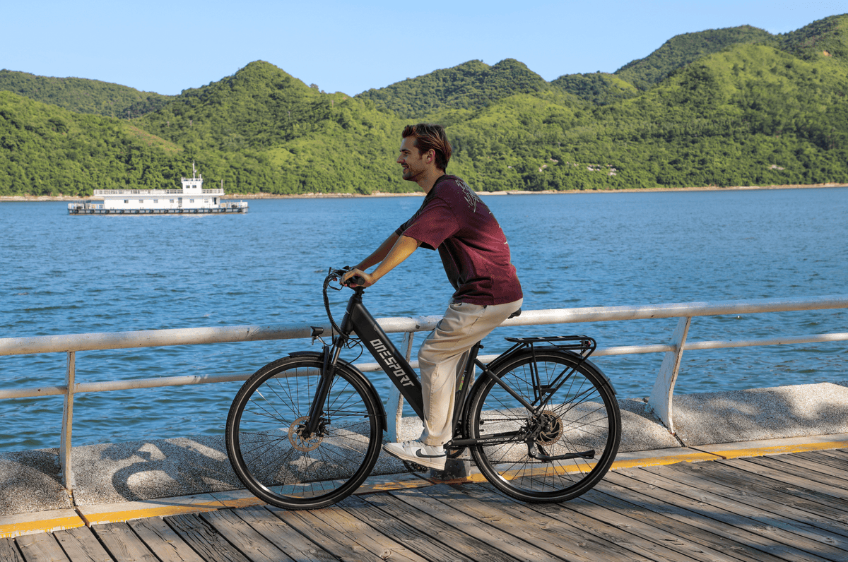 Personne roulant sur le vélo électrique OneSport OT12 coloris noir au bord de la mer