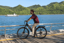 Personne roulant sur le vélo électrique OneSport OT12 coloris noir au bord de la mer