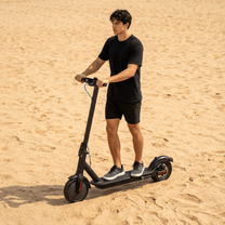 Homme debout avec la trottinette électrique SEEDREAM RED WING MINI sur un terrain sablonneux