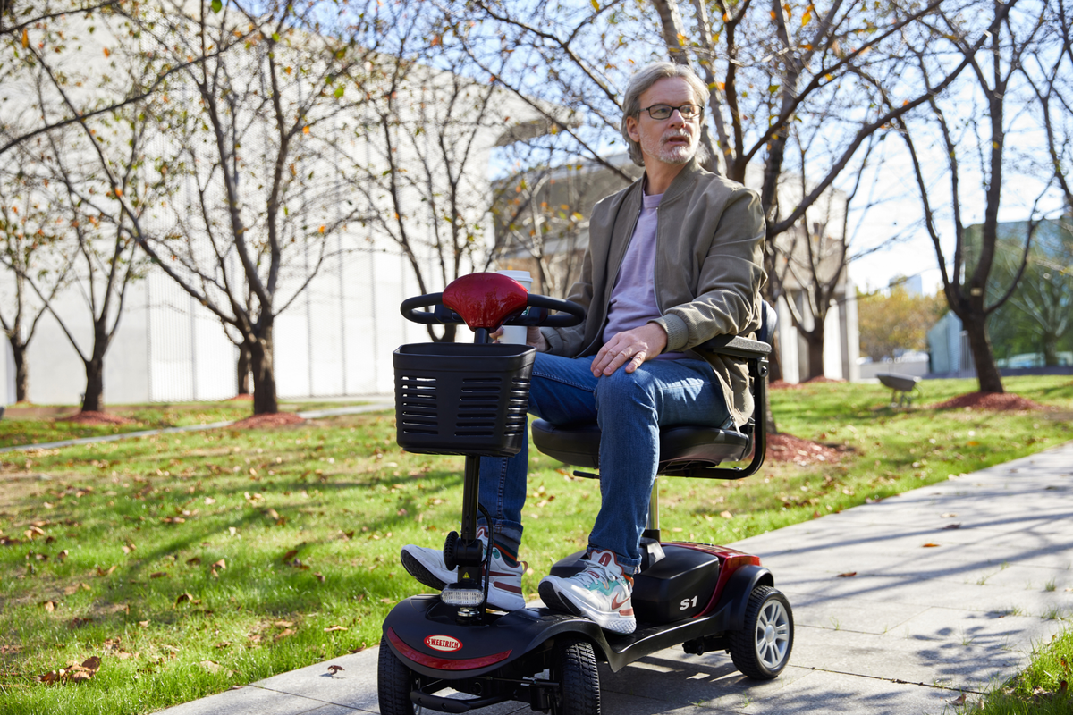 Homme assis sur le scooter de mobilité Sweetrich S1 Sport dans un parc