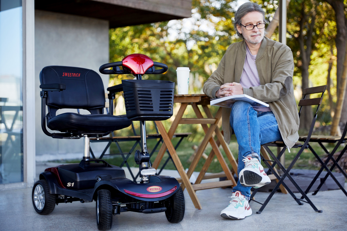 Personne assise à côté du scooter de mobilité Sweetrich S1 Sport