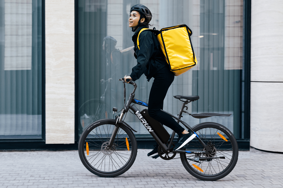Personne roulant sur le VTT électrique VARUN M24-1 coloris noir avec un casque en ville