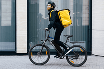 Personne roulant sur le VTT électrique VARUN M24-1 coloris noir avec un casque en ville