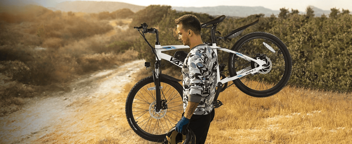 Homme debout avec le VTT électrique VARUN M24-1 coloris blanc sur une pelouse