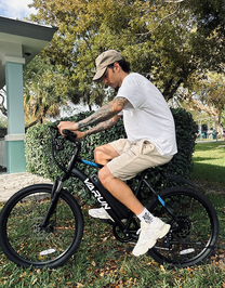 Homme roulant sur le VTT électrique VARUN M24-1 coloris noir dans un parc