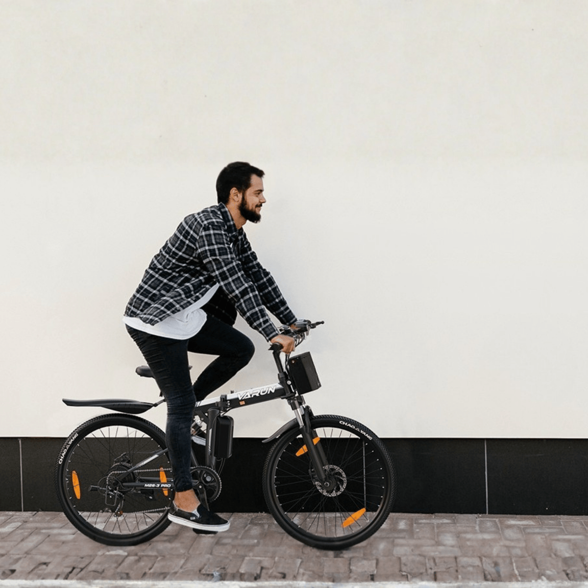 Homme roulant sur le VTT électrique VARUN M26-3 Pro coloris noir dans une rue