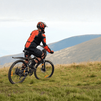 Homme roulant sur le VTT électrique VARUN M26-3 Pro coloris noir avec un casque en montagne