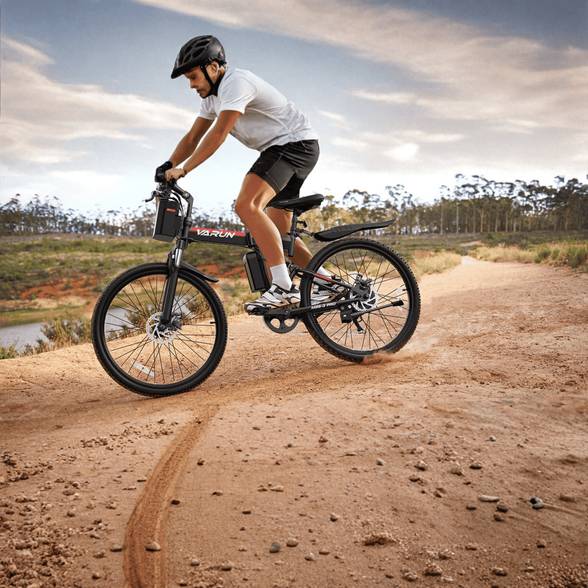 Homme roulant sur le VTT électrique VARUN M26-3 Pro coloris noir avec un casque sur un sentier