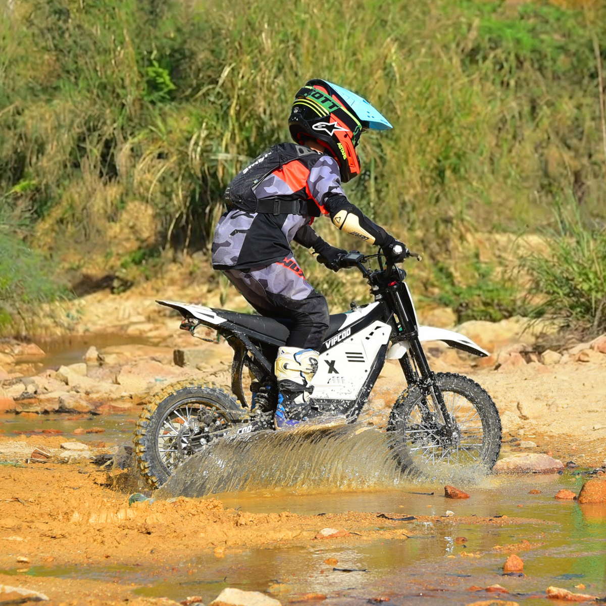 Pilote sur la moto-cross électrique Vipcoo H2 en tout-terrain sur un terrain sablonneux