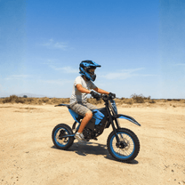 Pilote sur la moto-cross électrique ZAWES S3 en tout-terrain sur un terrain sablonneux